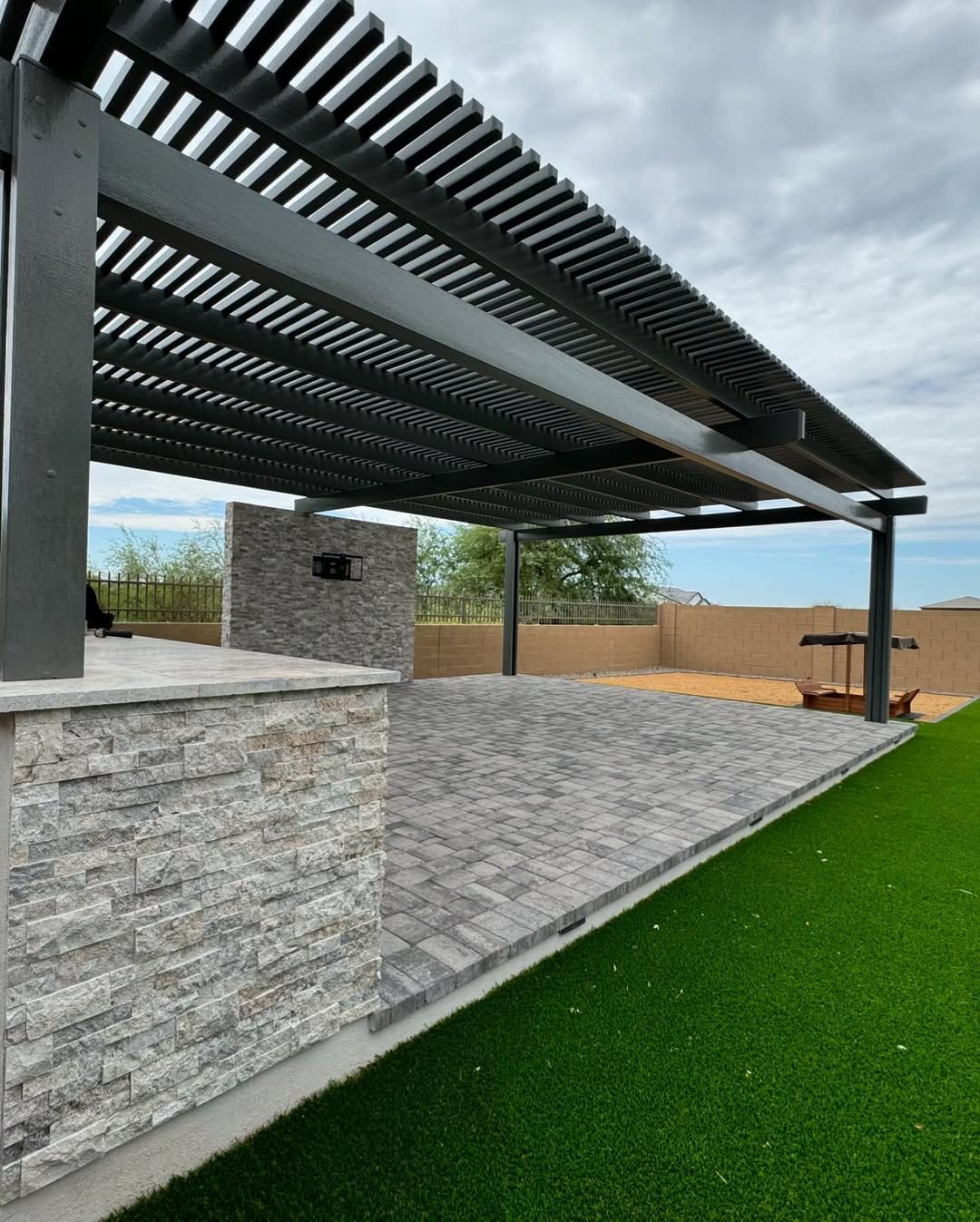A patio with a pergola and a brick walkway.