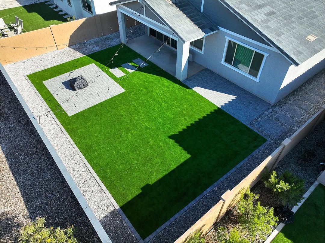 An aerial view of a house with a large lawn and a fire pit.