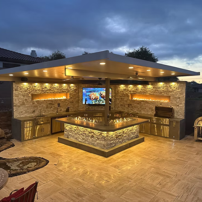 A large outdoor kitchen with a television on the wall.