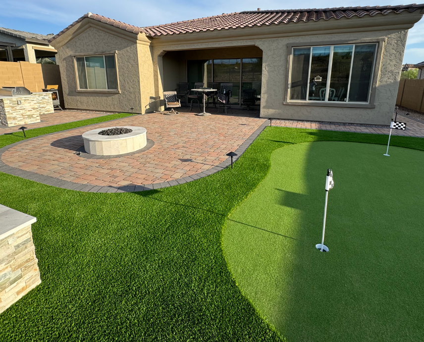 There is a putting green in the backyard of a house.