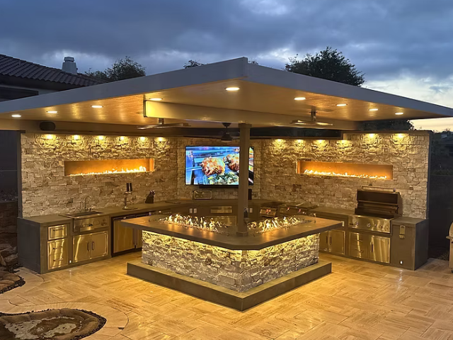 A large outdoor kitchen with a television on the wall.