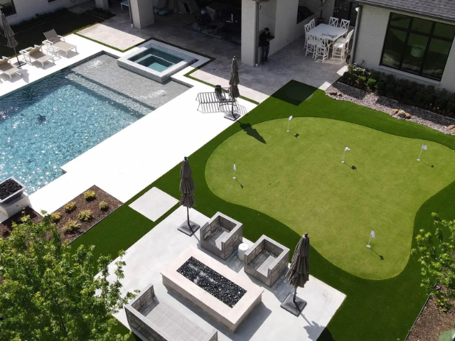 An aerial view of a backyard with a swimming pool and a putting green