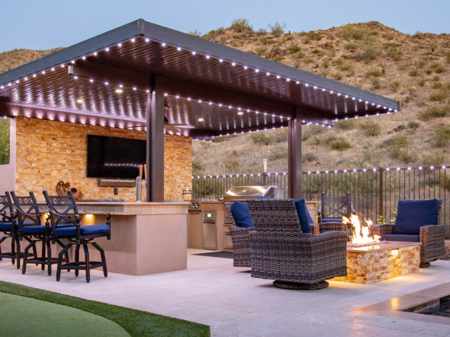 A patio area with a fire pit and chairs under a canopy