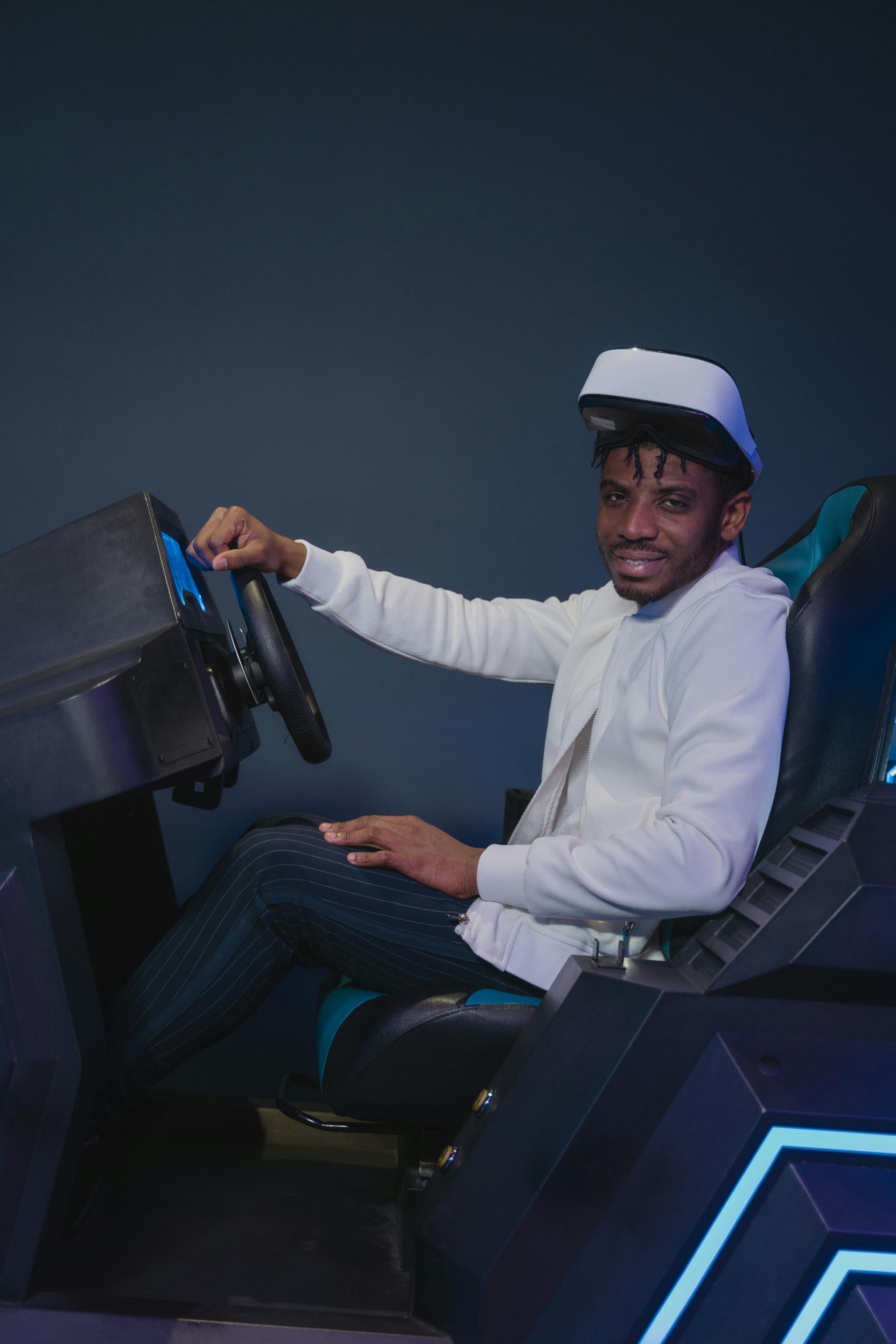 Man wearing VR headset, sitting in a racing simulator, smiling.