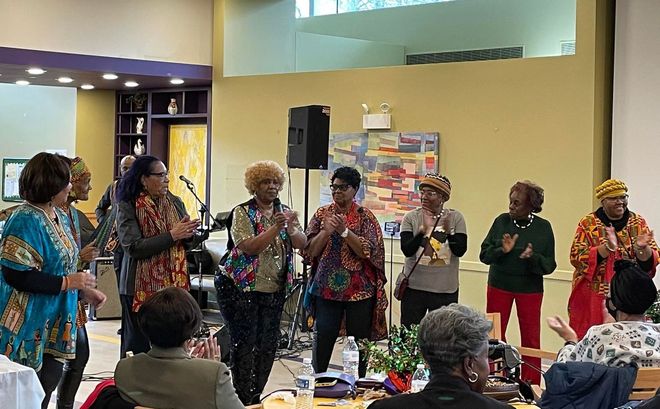 A group of women are standing in front of a microphone in a room.