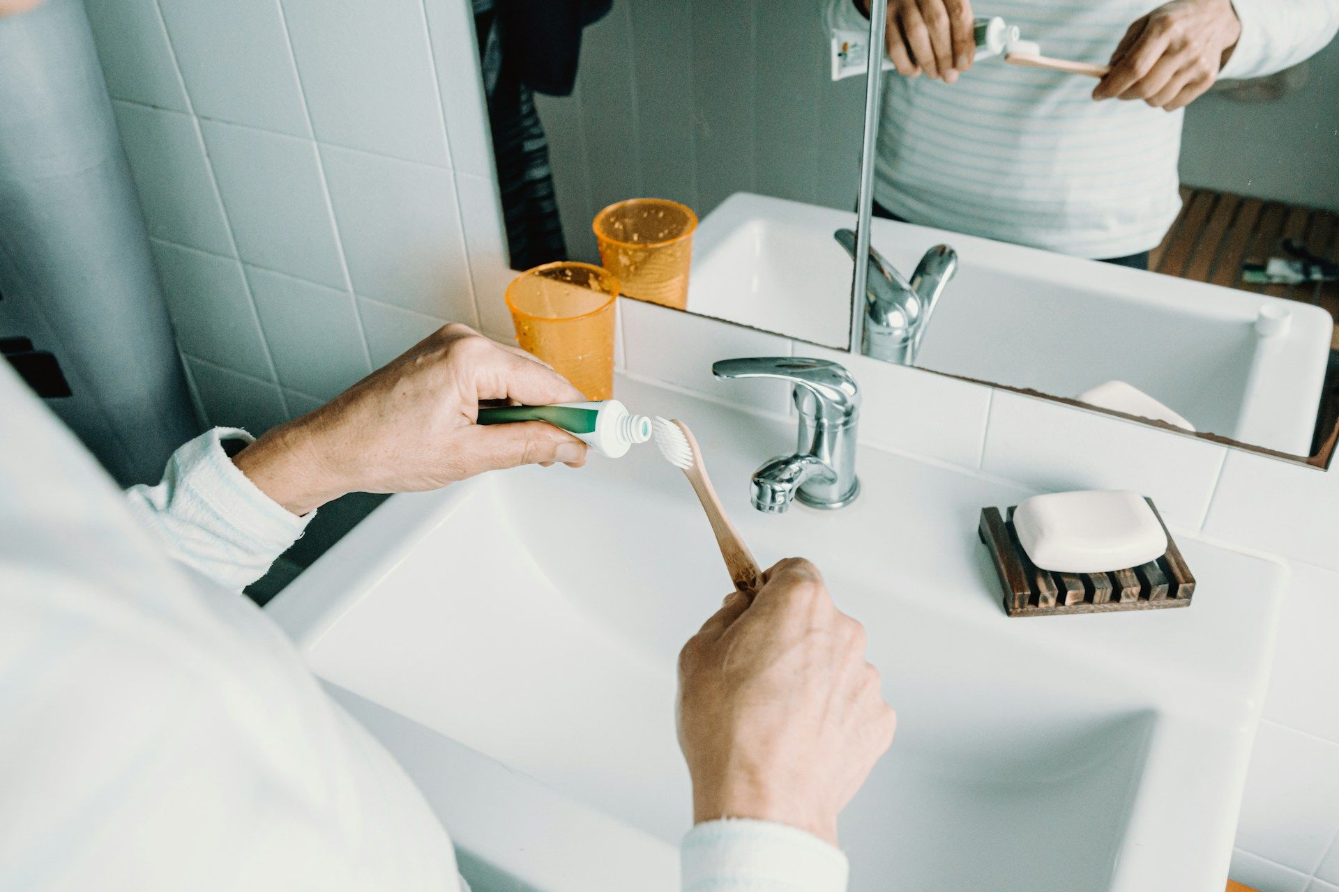 A person is brushing their teeth in a bathroom sink.