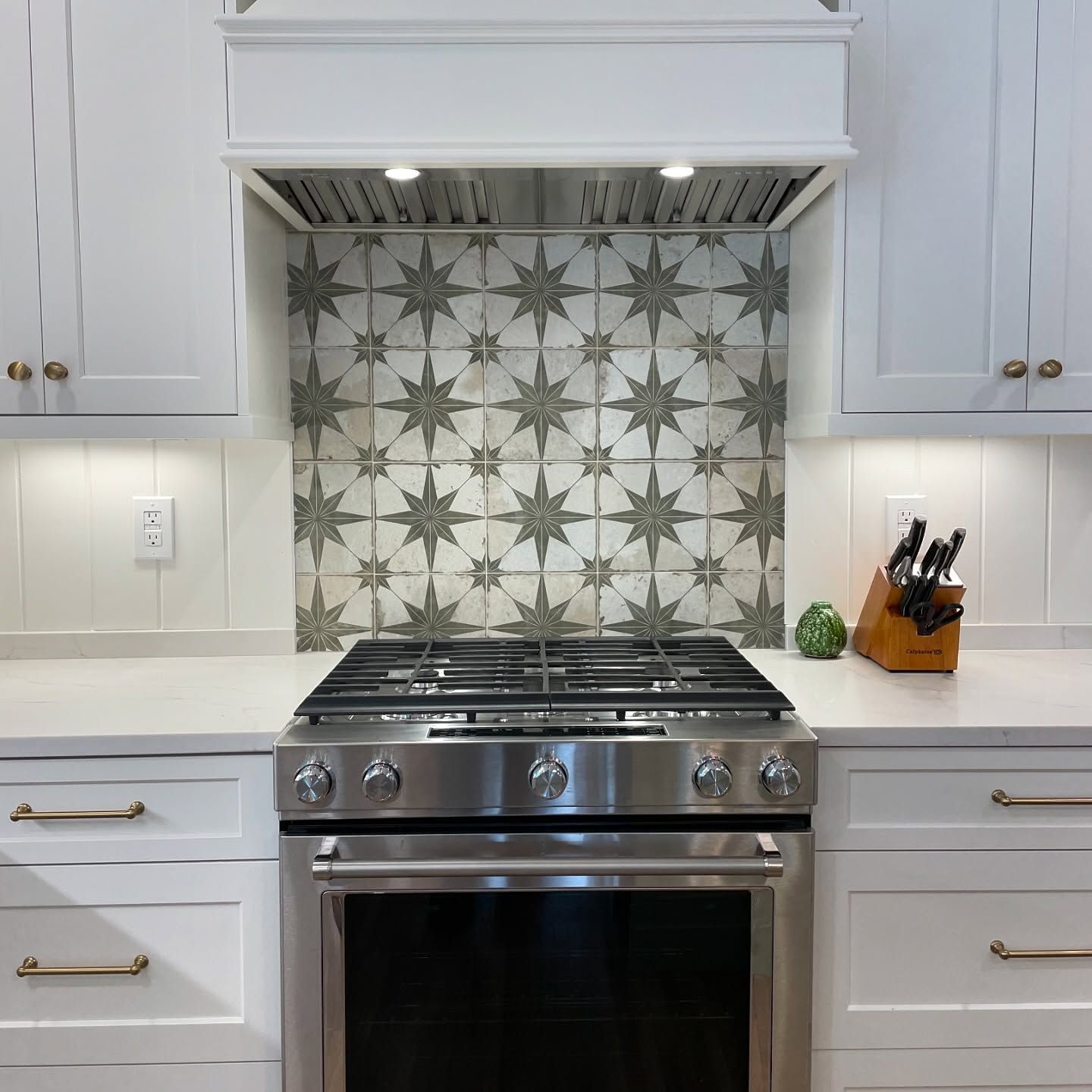 A kitchen with a stove top oven and white cabinets