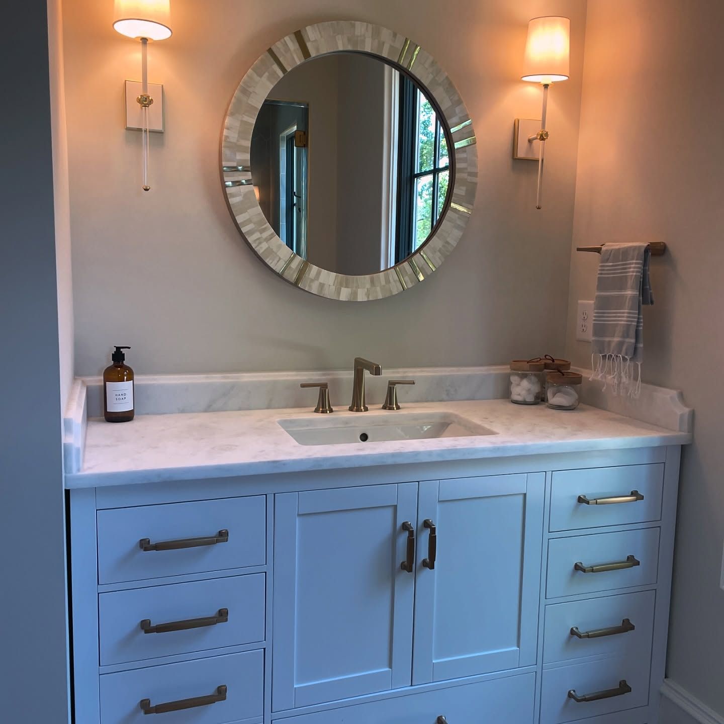 A bathroom with a sink and a round mirror
