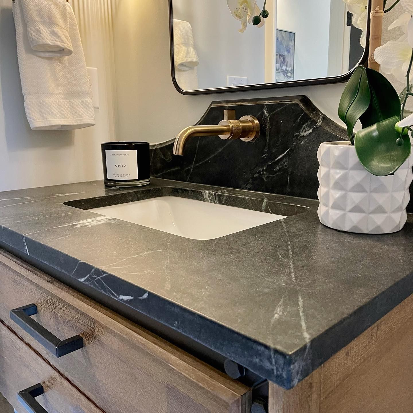 A bathroom sink with a marble counter top and a mirror.
