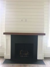 A fireplace with a wooden mantle in a living room.