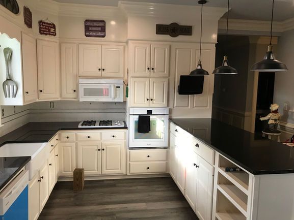 A kitchen with white cabinets and black counter tops