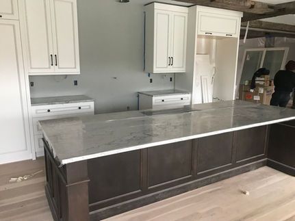 A kitchen with white cabinets and a large island in the middle.