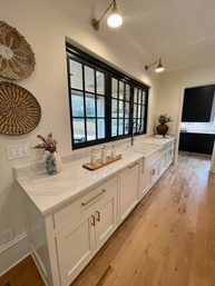A kitchen with white cabinets and a large window
