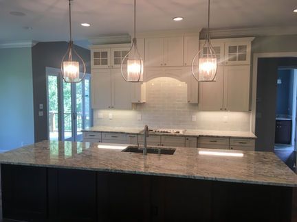 A kitchen with white cabinets , granite counter tops , and a large island.
