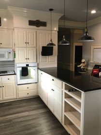 A kitchen with white cabinets , black counter tops , and a large island.