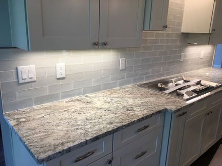 A kitchen with granite counter tops and white cabinets.