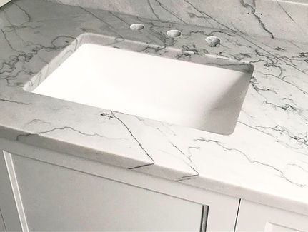 A white sink is sitting on top of a marble counter top.