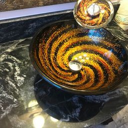 A bathroom sink with a swirl design on it is on a counter.