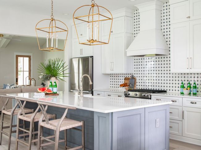 A kitchen with white cabinets and a large island with stools.
