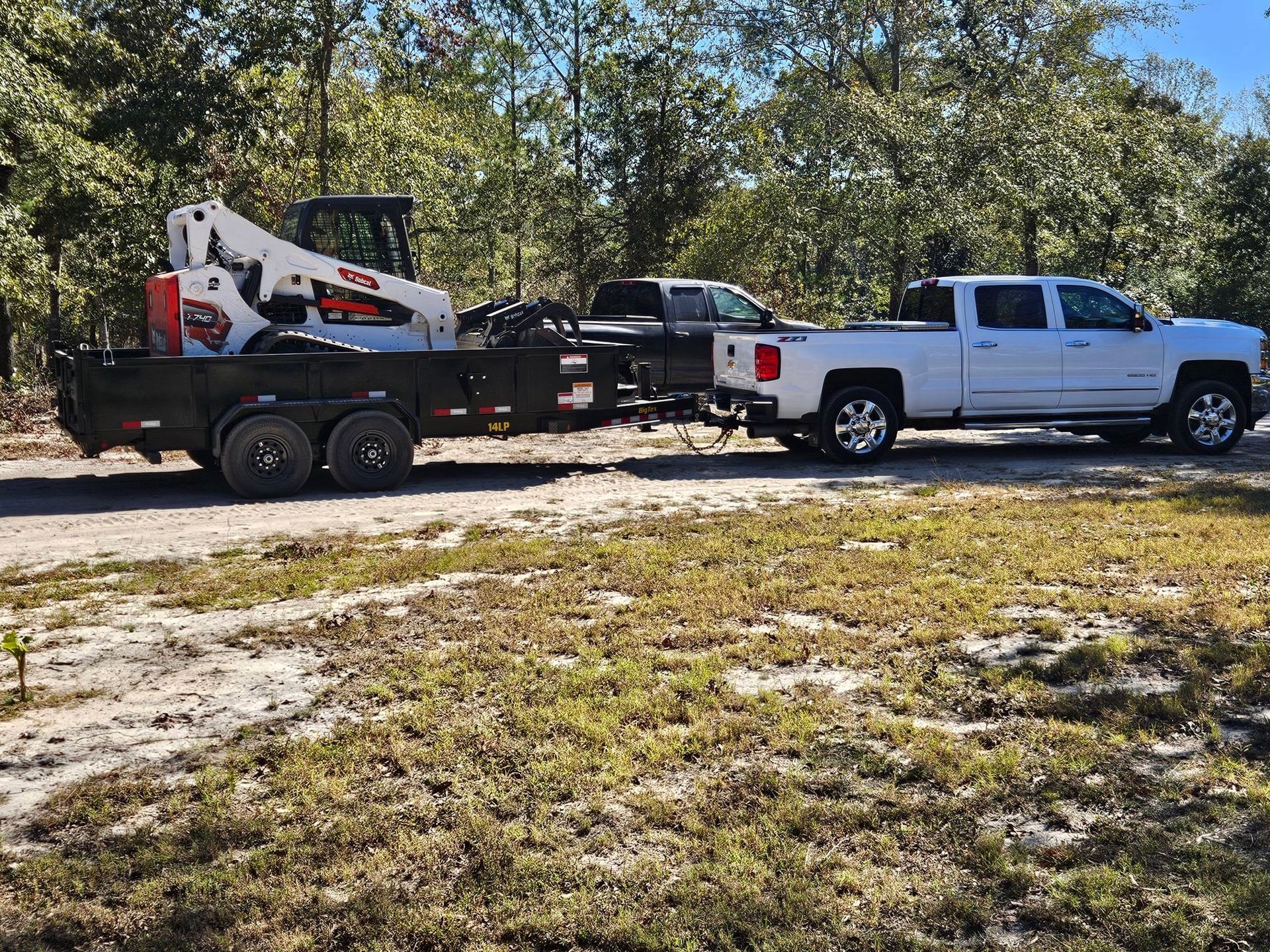 A white truck is towing a trailer with a bulldozer on it.