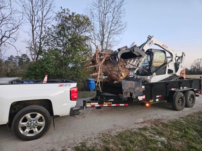 A white truck is towing a trailer with a bulldozer on it.