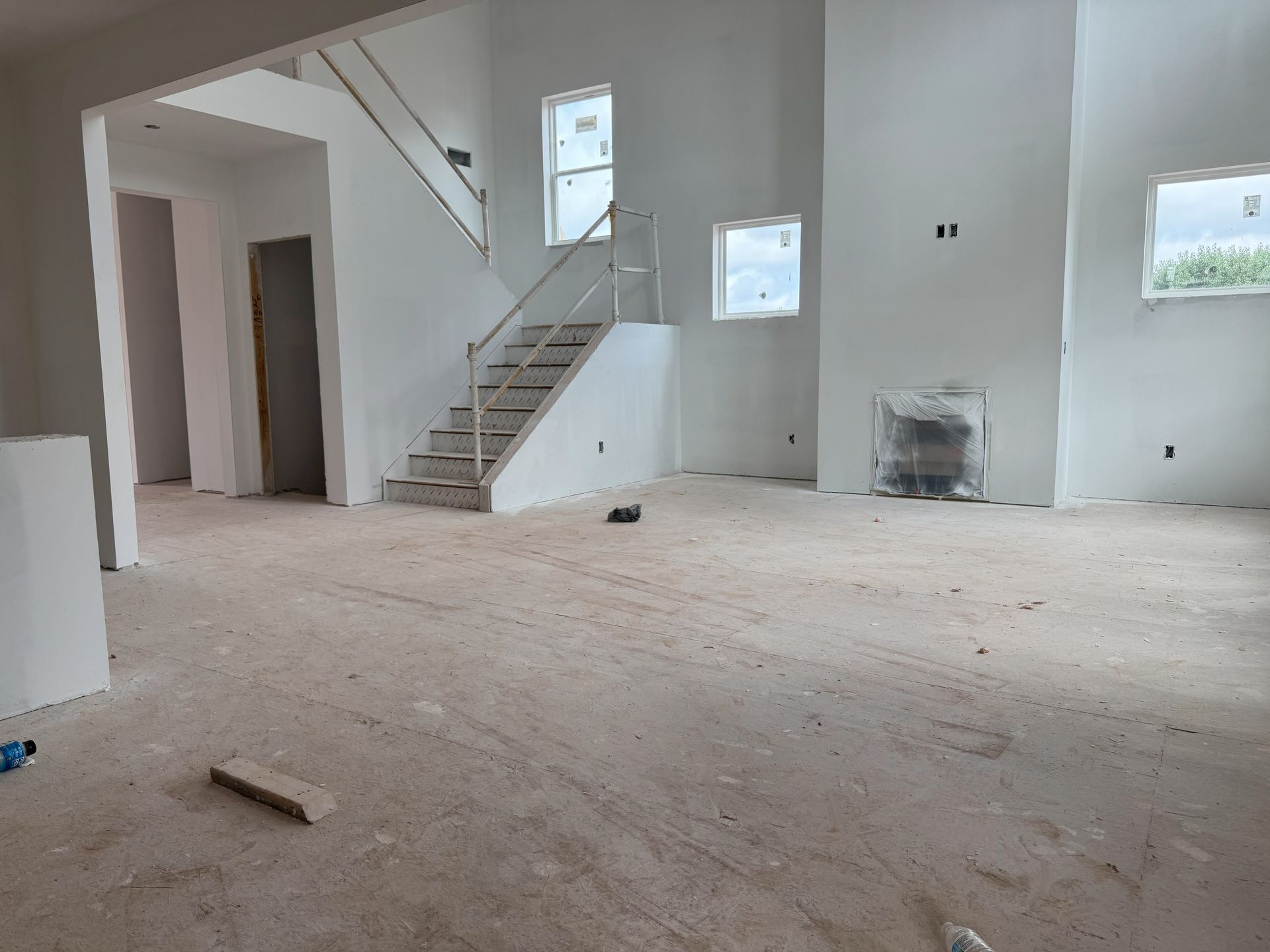 A large empty room with a staircase in the background.