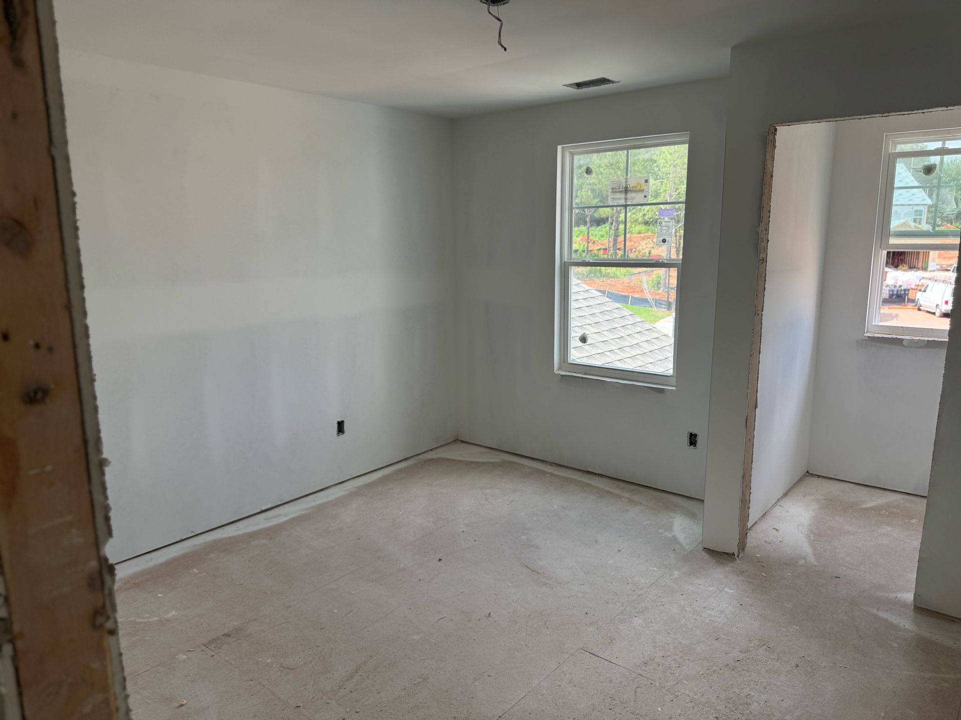 An empty room with white walls and a window in a house under construction.
