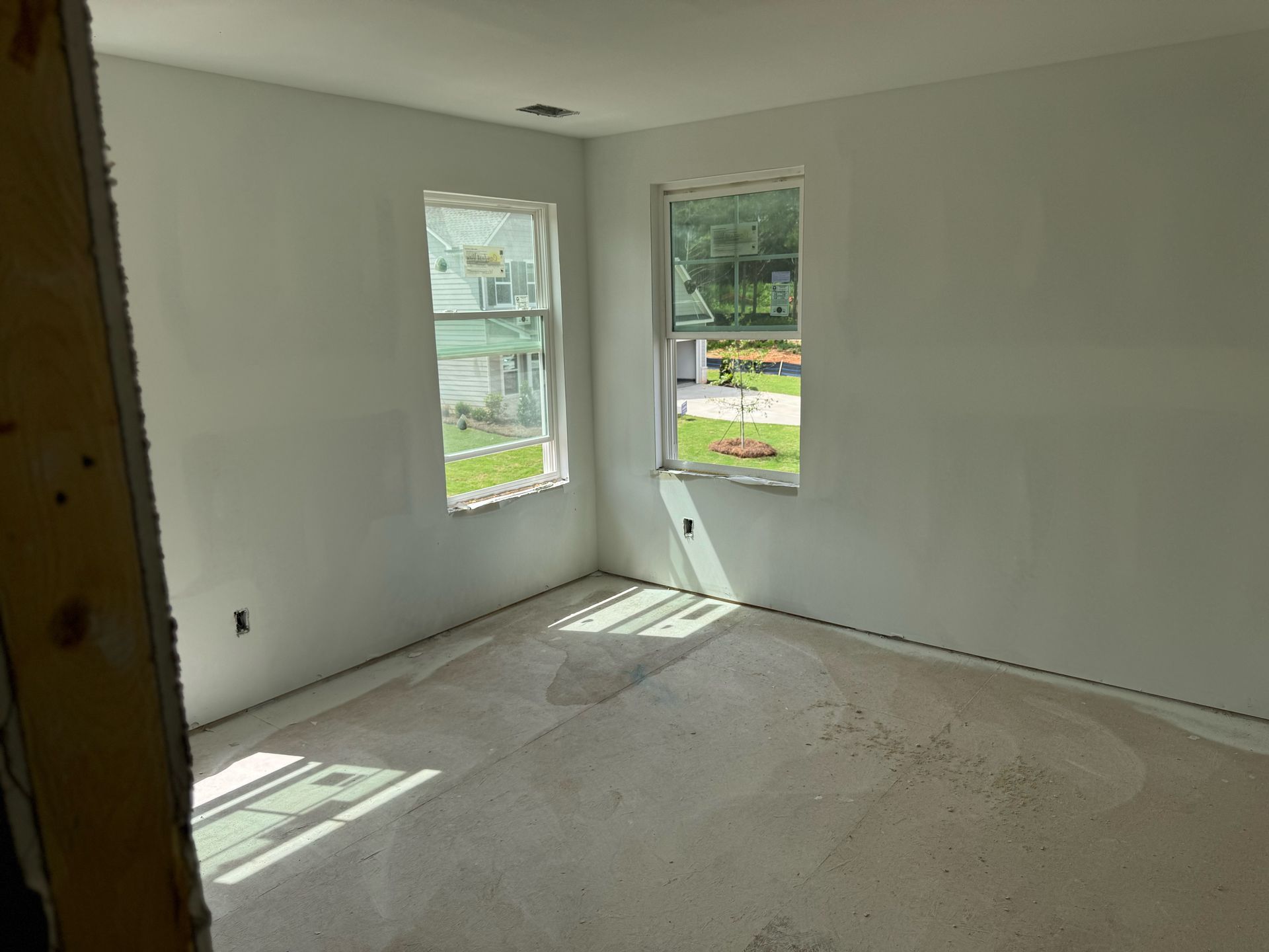 An empty room with two windows and a carpeted floor