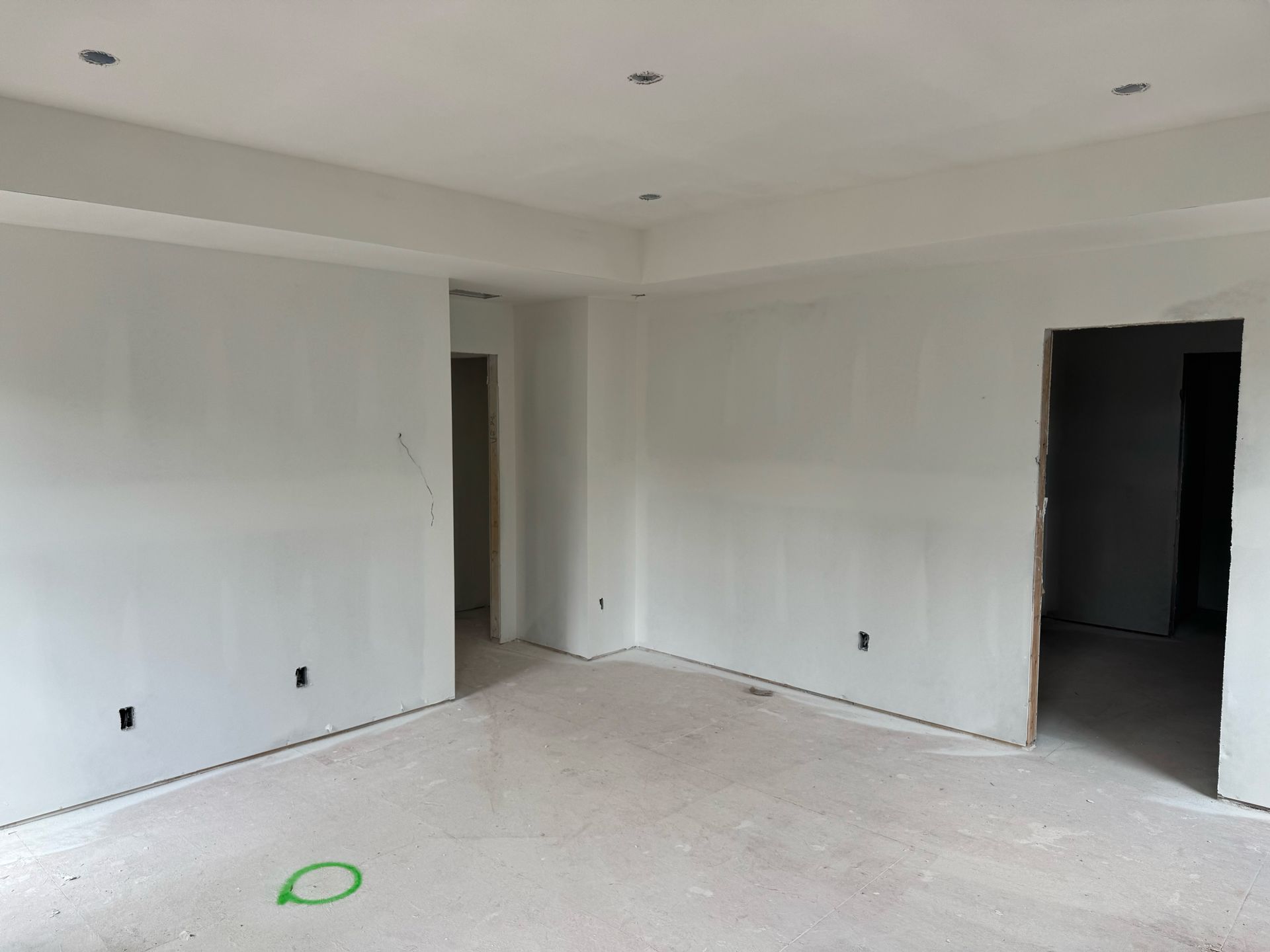 An empty room with white walls and a green circle on the floor.