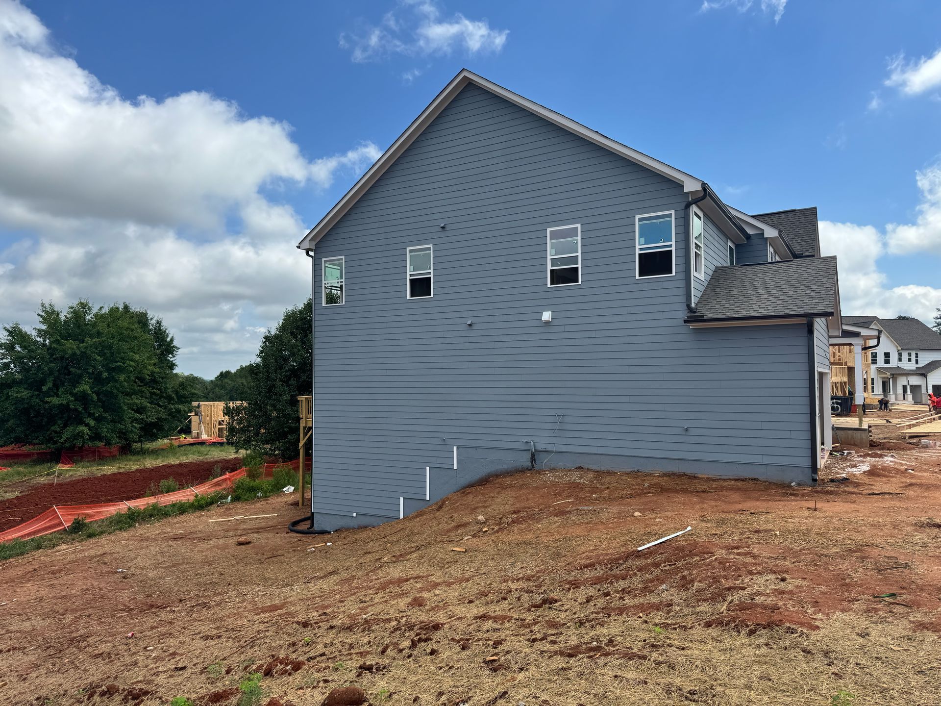 A large gray house is being built in a residential area.