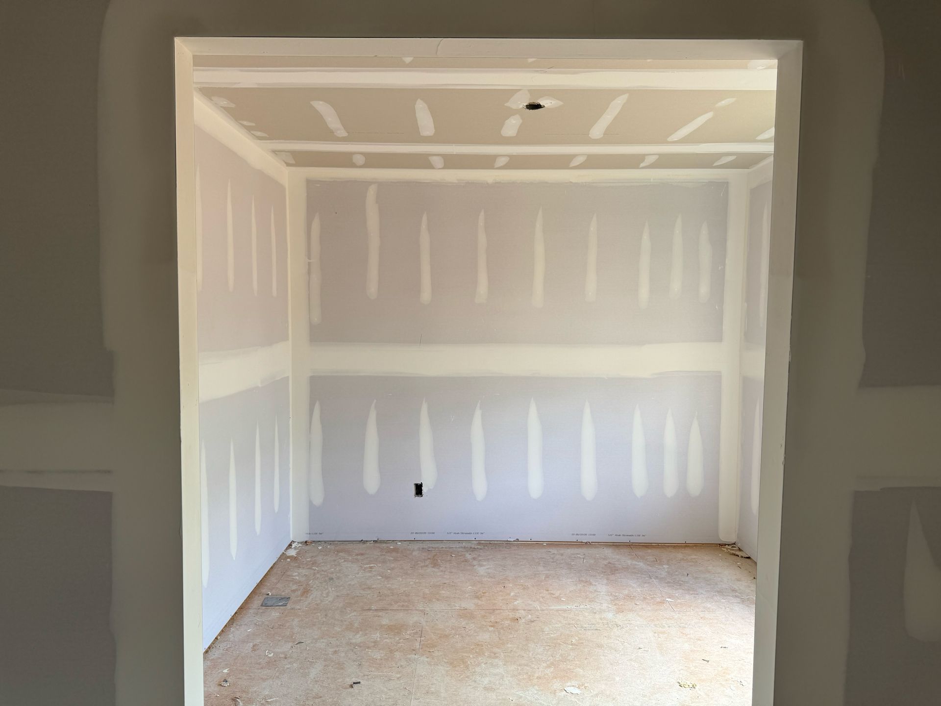 An empty room with drywall on the walls and ceiling
