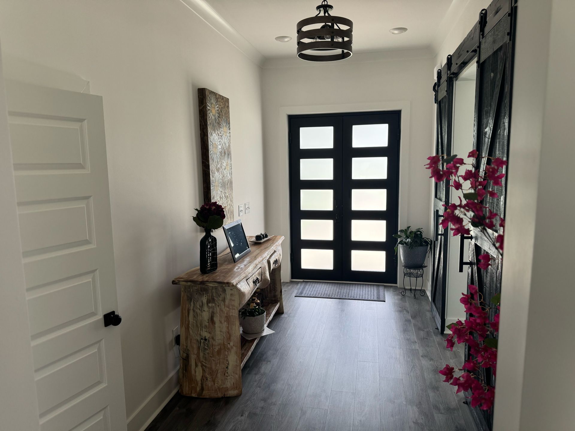 A hallway in a house with a black door and a wooden table.