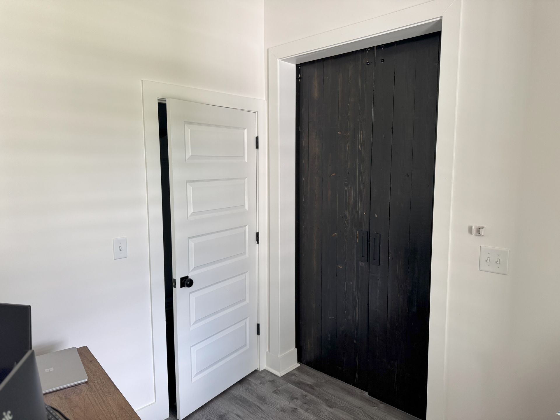 A white door is open to a black door in a room.