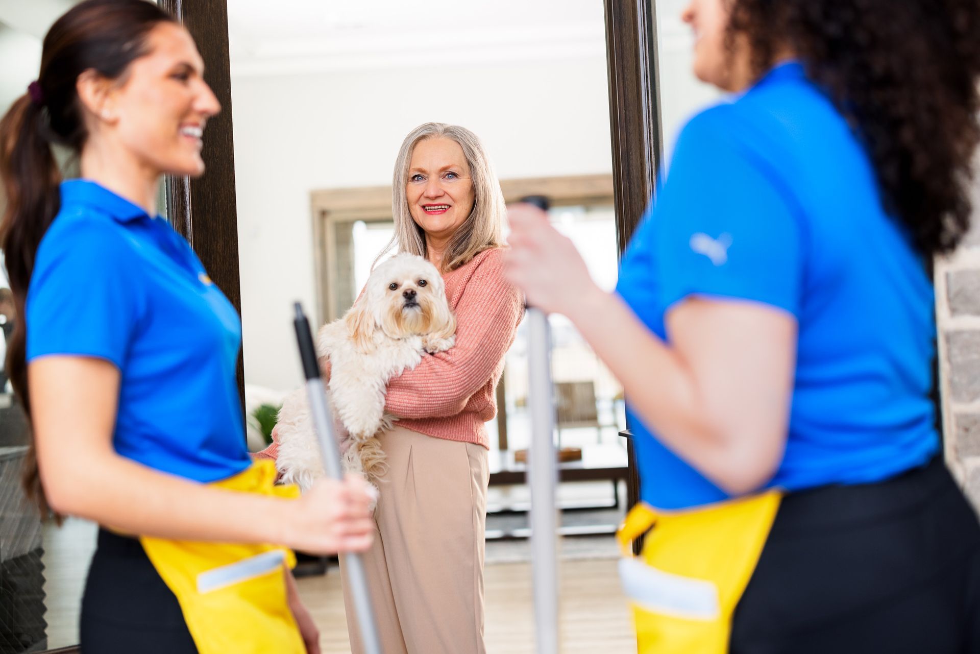 Two cleaners are standing next to a woman holding a dog.