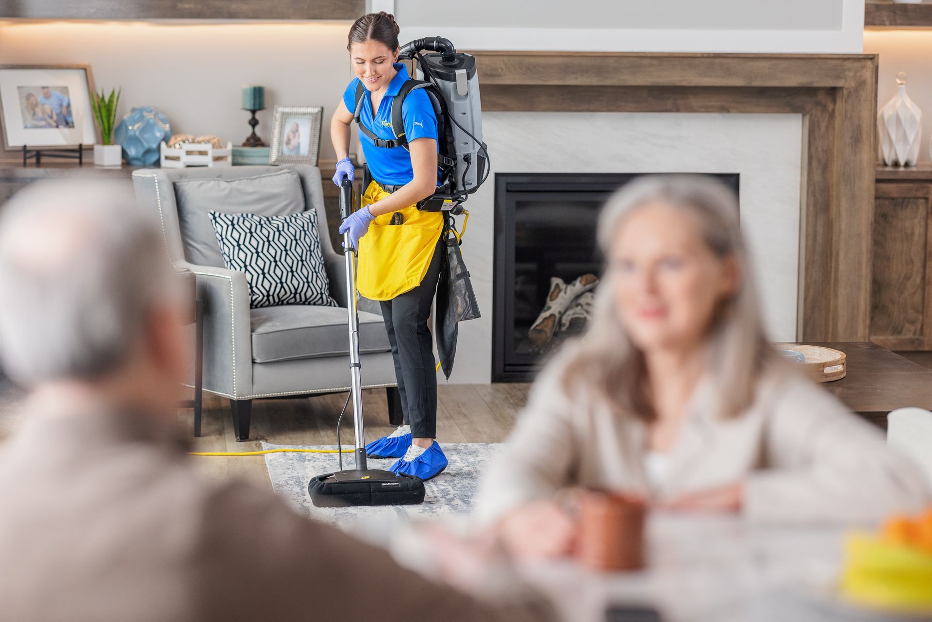 A woman is cleaning a living room with a vacuum cleaner.