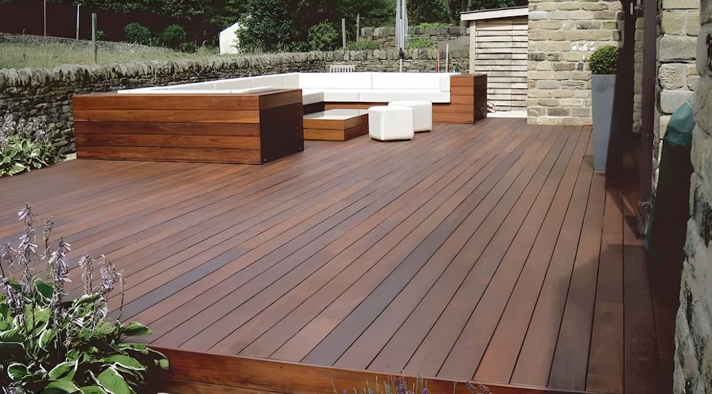 Wooden Deck With Outdoor Seating, Near Stone Wall and Greenery — CAW Services in Badagarang, NSW