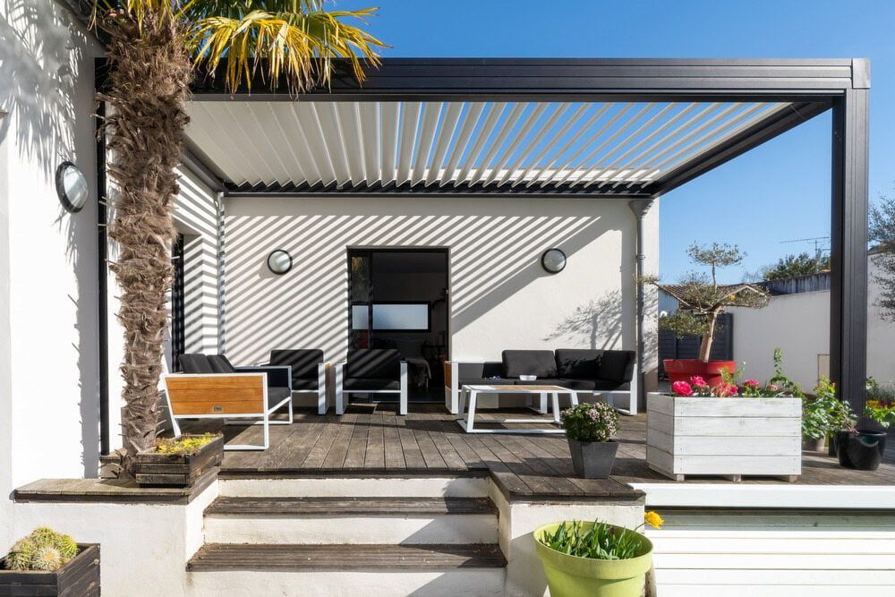 Patio With Pergola, Wooden Deck, Modern Furniture, Potted Plants, and White Walls — CAW Services in Badagarang, NSW