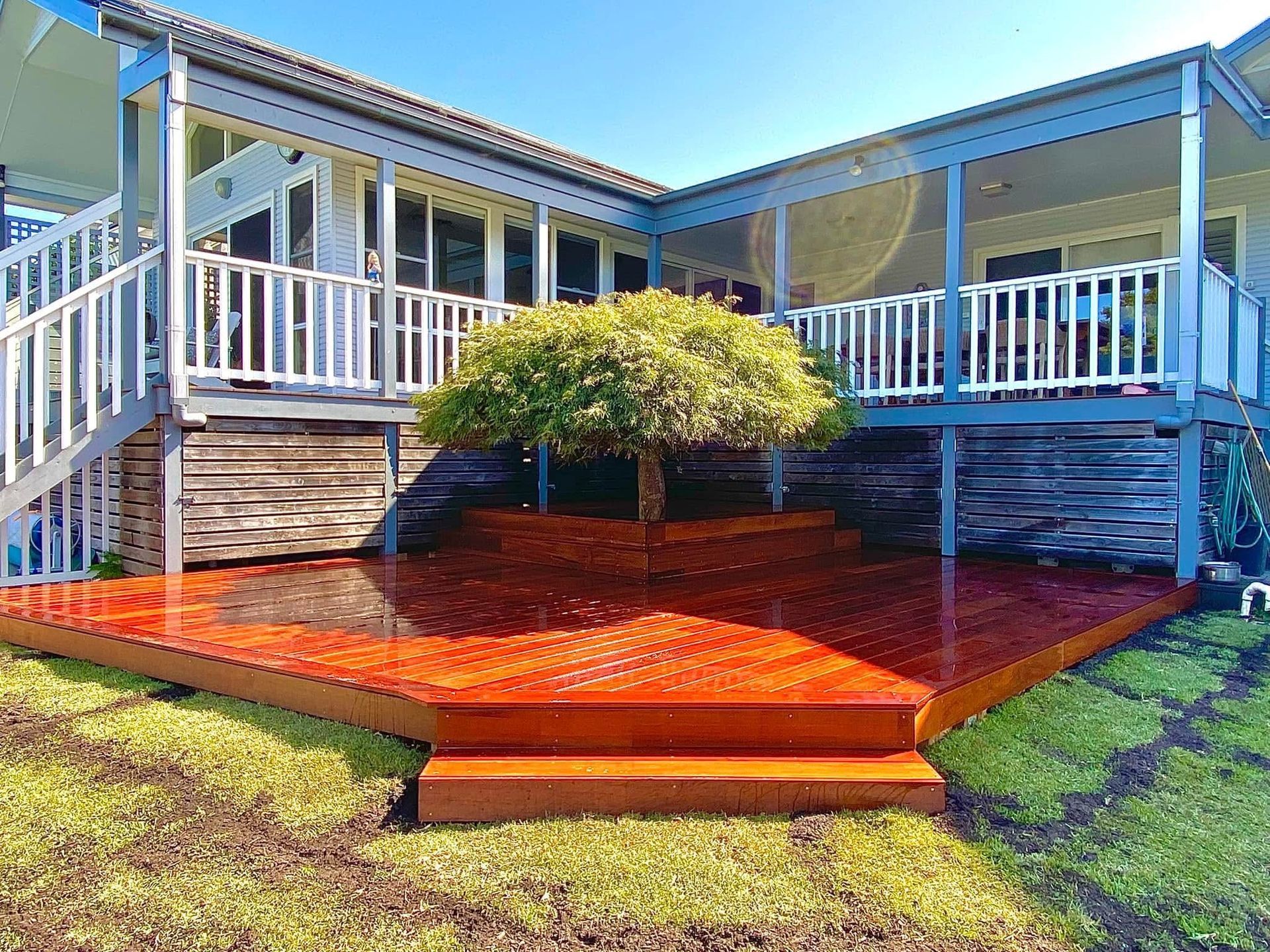 Wooden deck with tree, stairs, and house in background; sunny day. — CAW Services in Badagarang, NSW