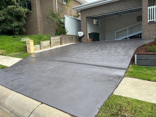Dark Grey Concrete Driveway Leading to A Garage — CAW Services in Badagarang, NSW