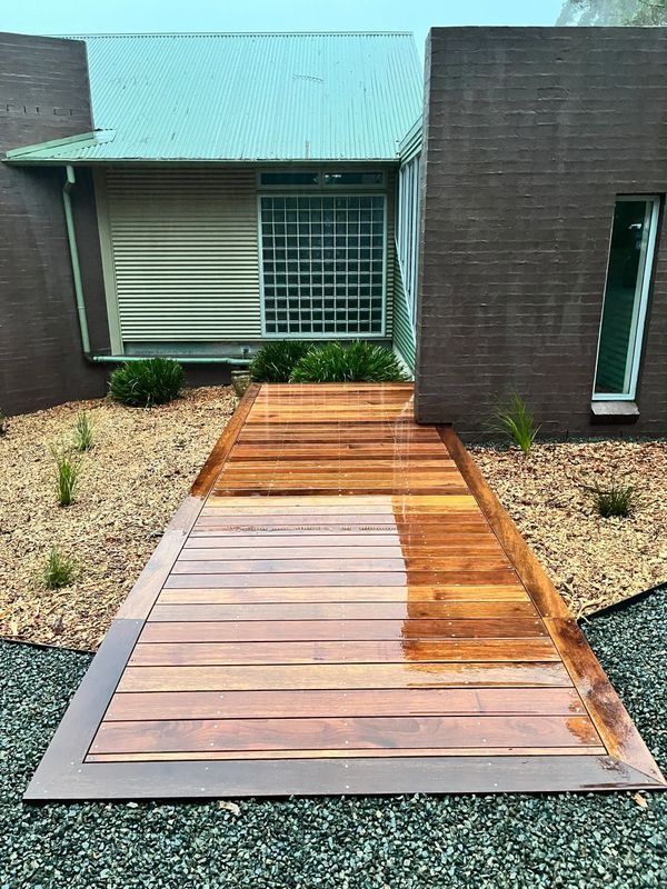 Wooden Walkway Leading to A Modern Building with A Green Roof — CAW Services in Badagarang, NSW