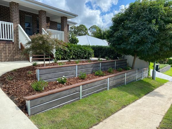 A House with A Brick Facade and A Multi-Level Retaining Wall with Plants — CAW Services in Badagarang, NSW