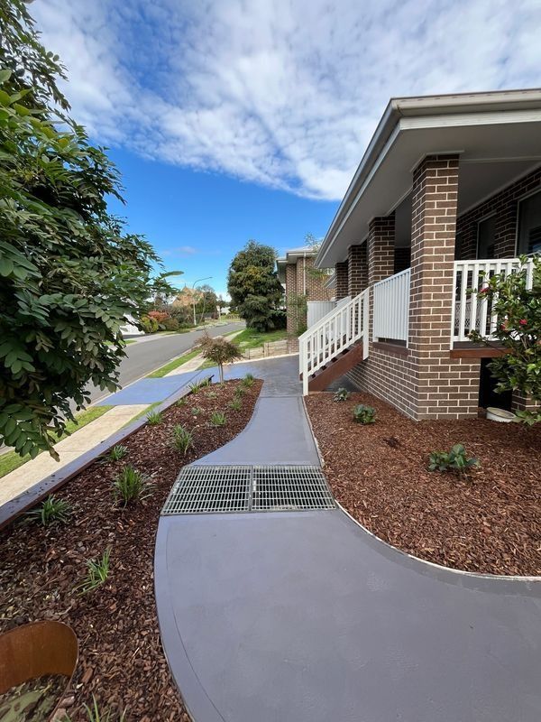 Exterior of A Brick House with A Curved Grey Walkway and Landscaping — CAW Services in Badagarang, NSW