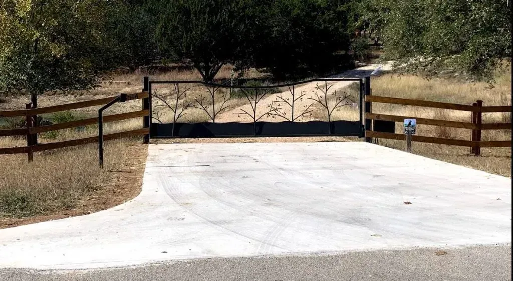 A driveway with a gate and a wooden fence