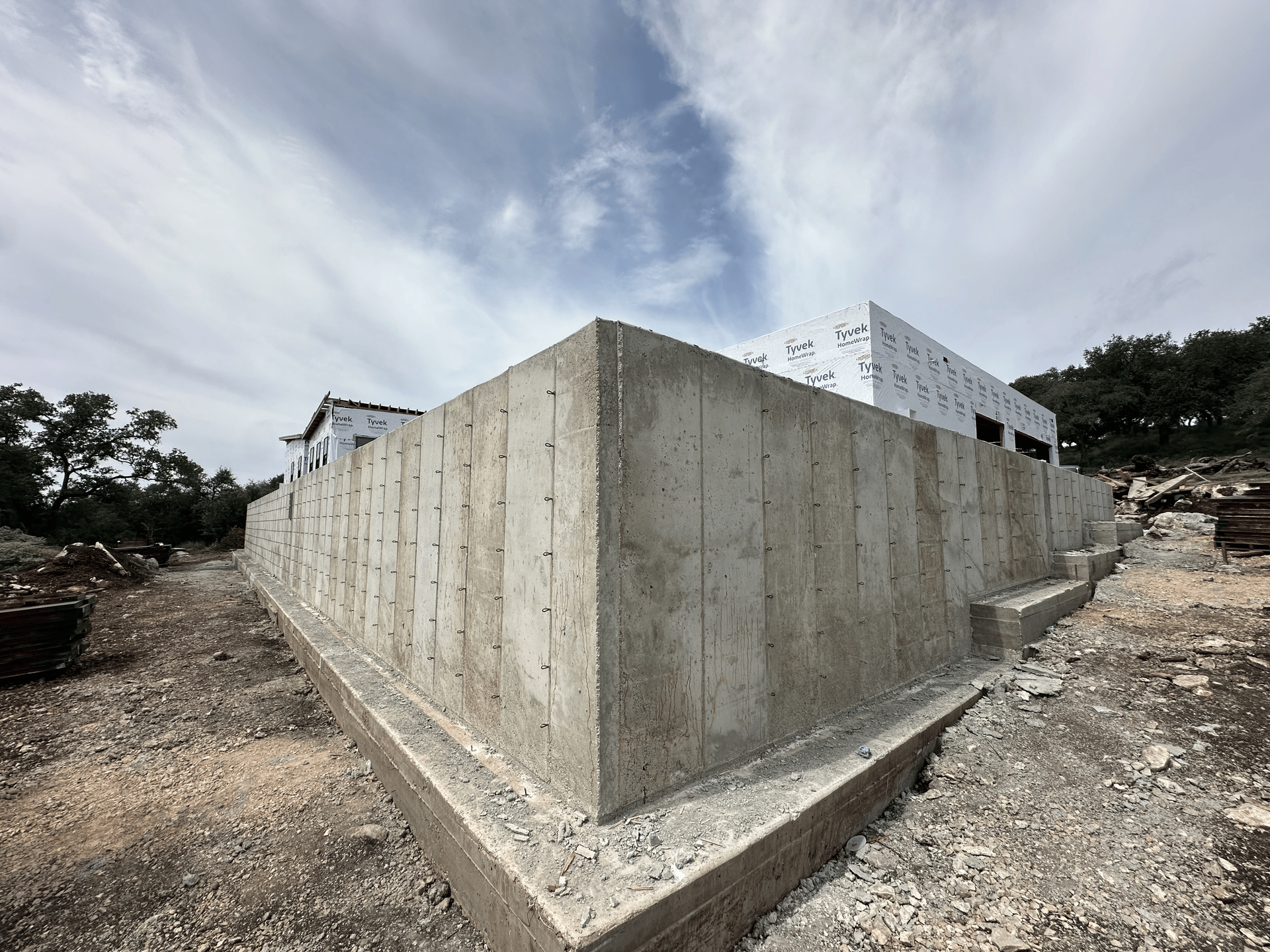 Concrete foundation of a building under construction, exterior view, with sky in the background.