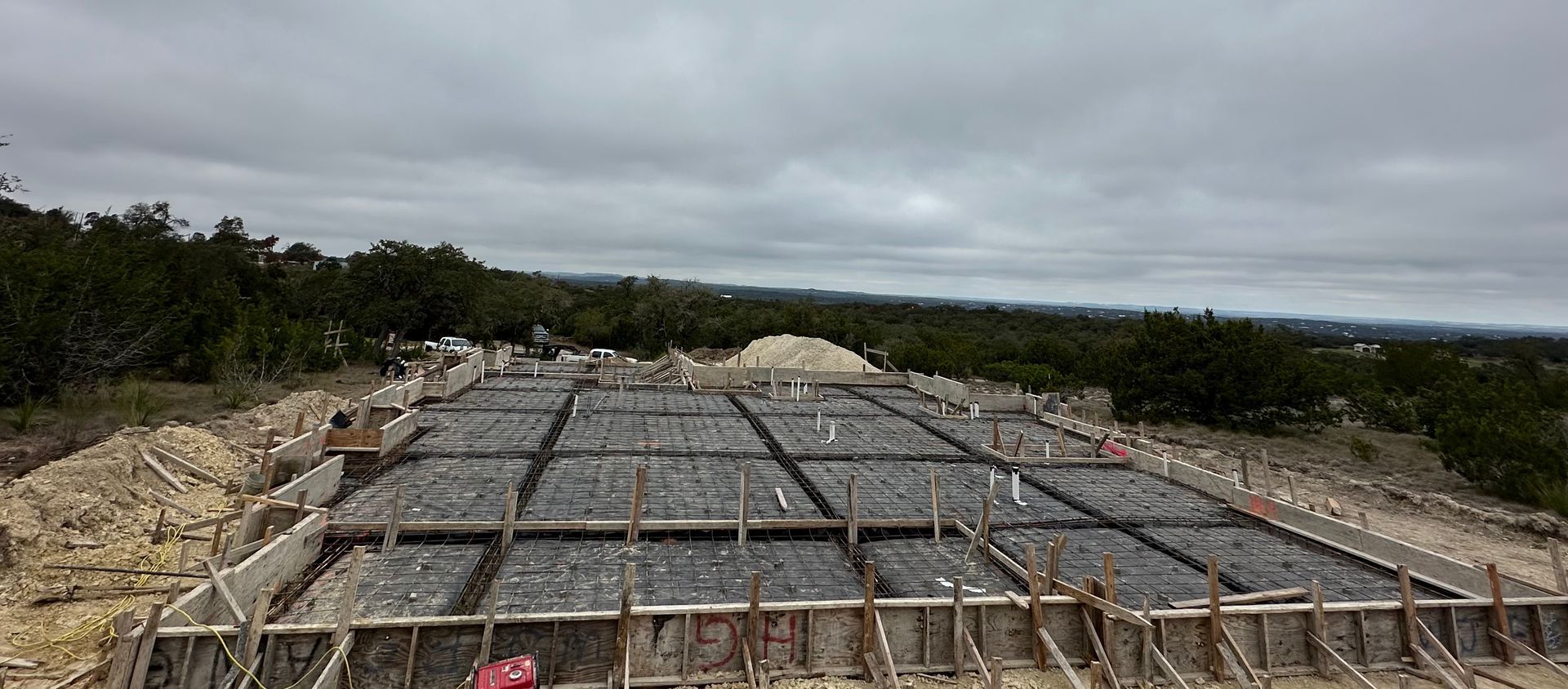 A concrete foundation is being built on top of a dirt hill.