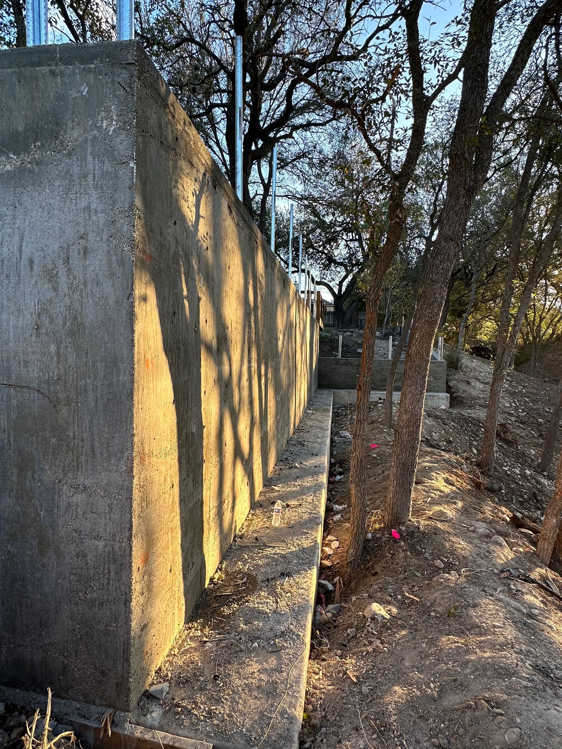A concrete wall with trees in the background is being built.