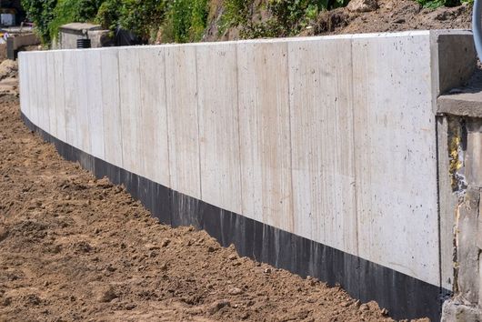 A concrete wall is being built on top of a dirt field.