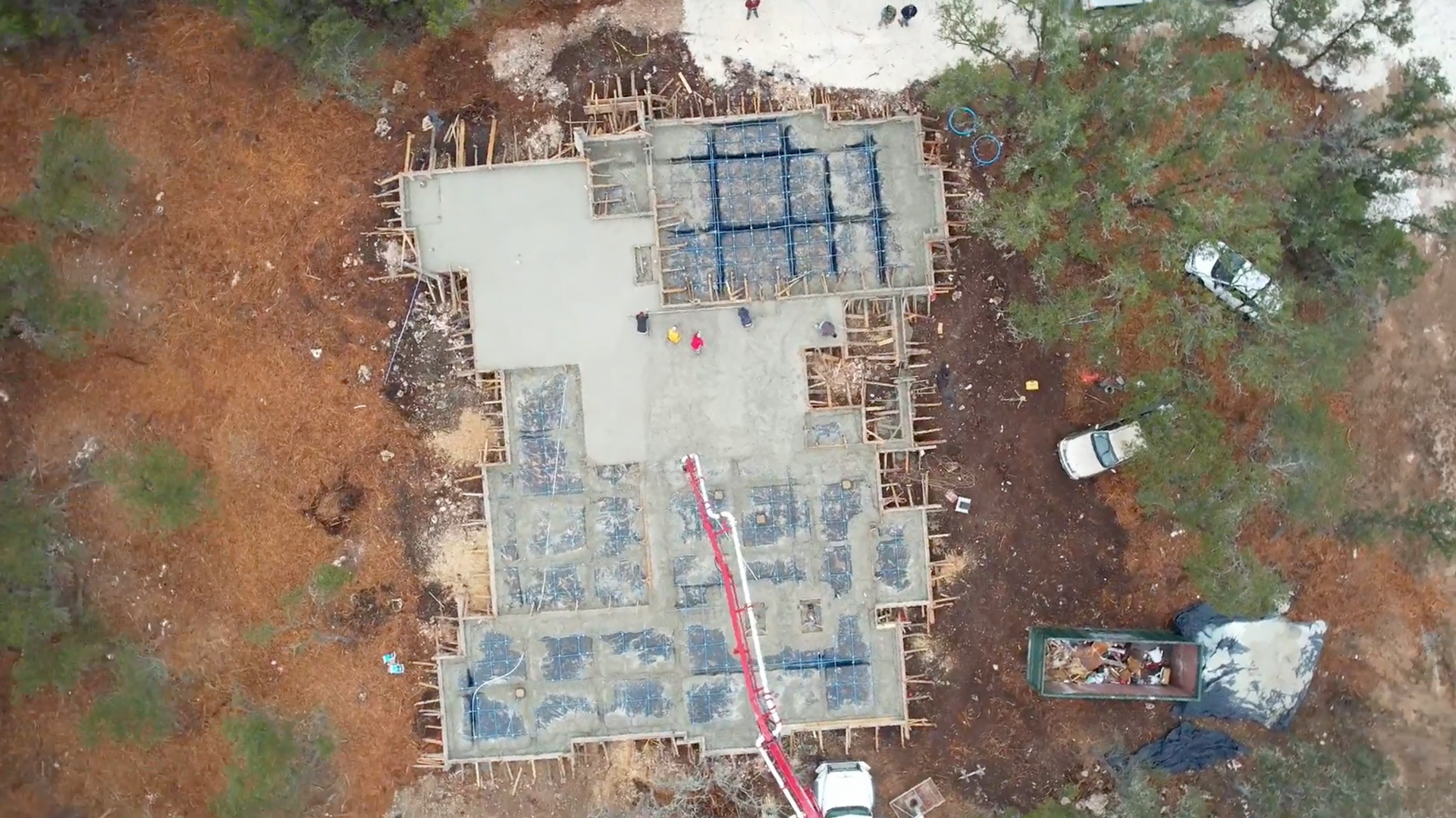 An aerial view of a building under construction in the middle of a forest.
