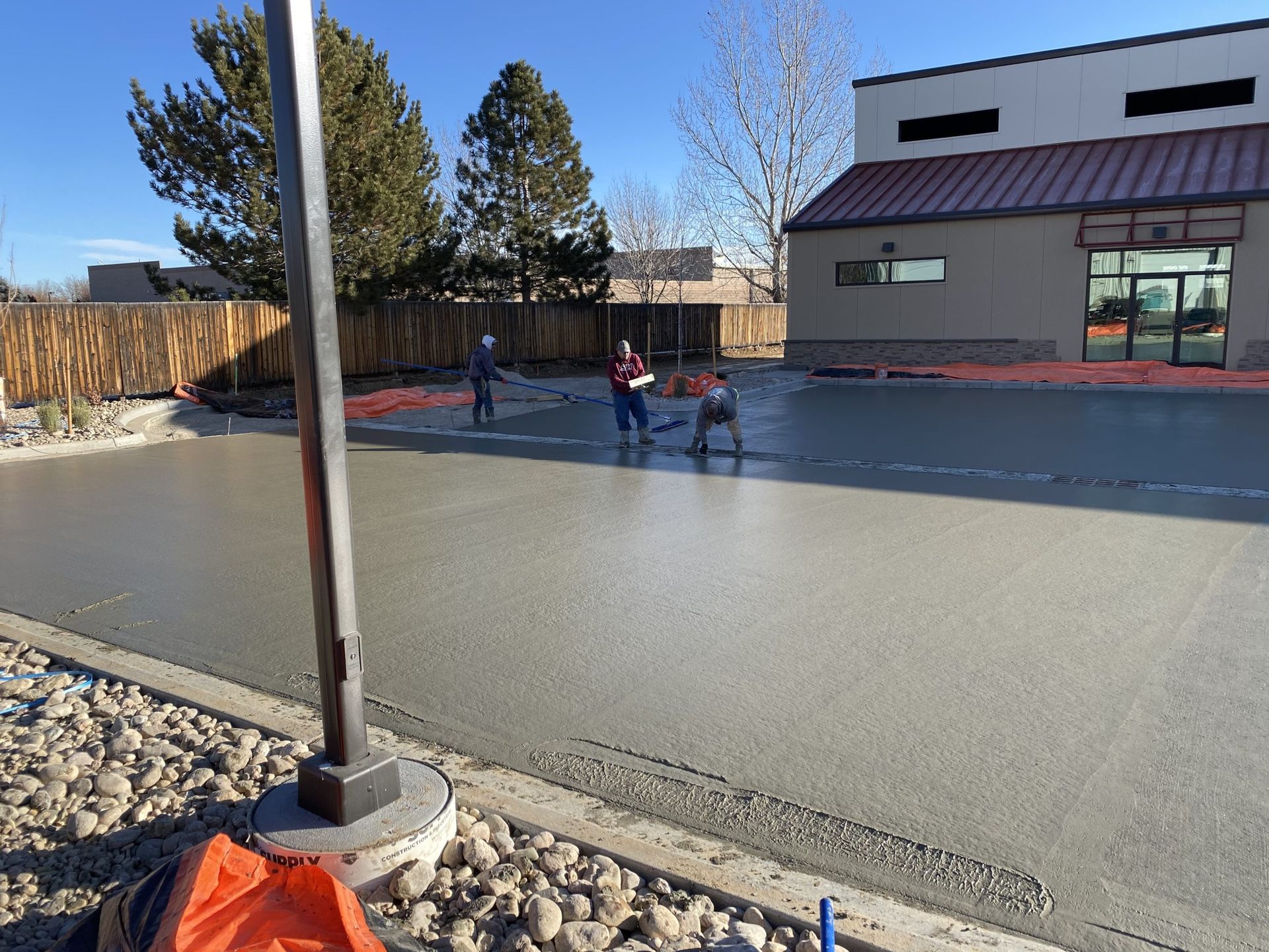 A group of people are working on a concrete driveway in front of a building.