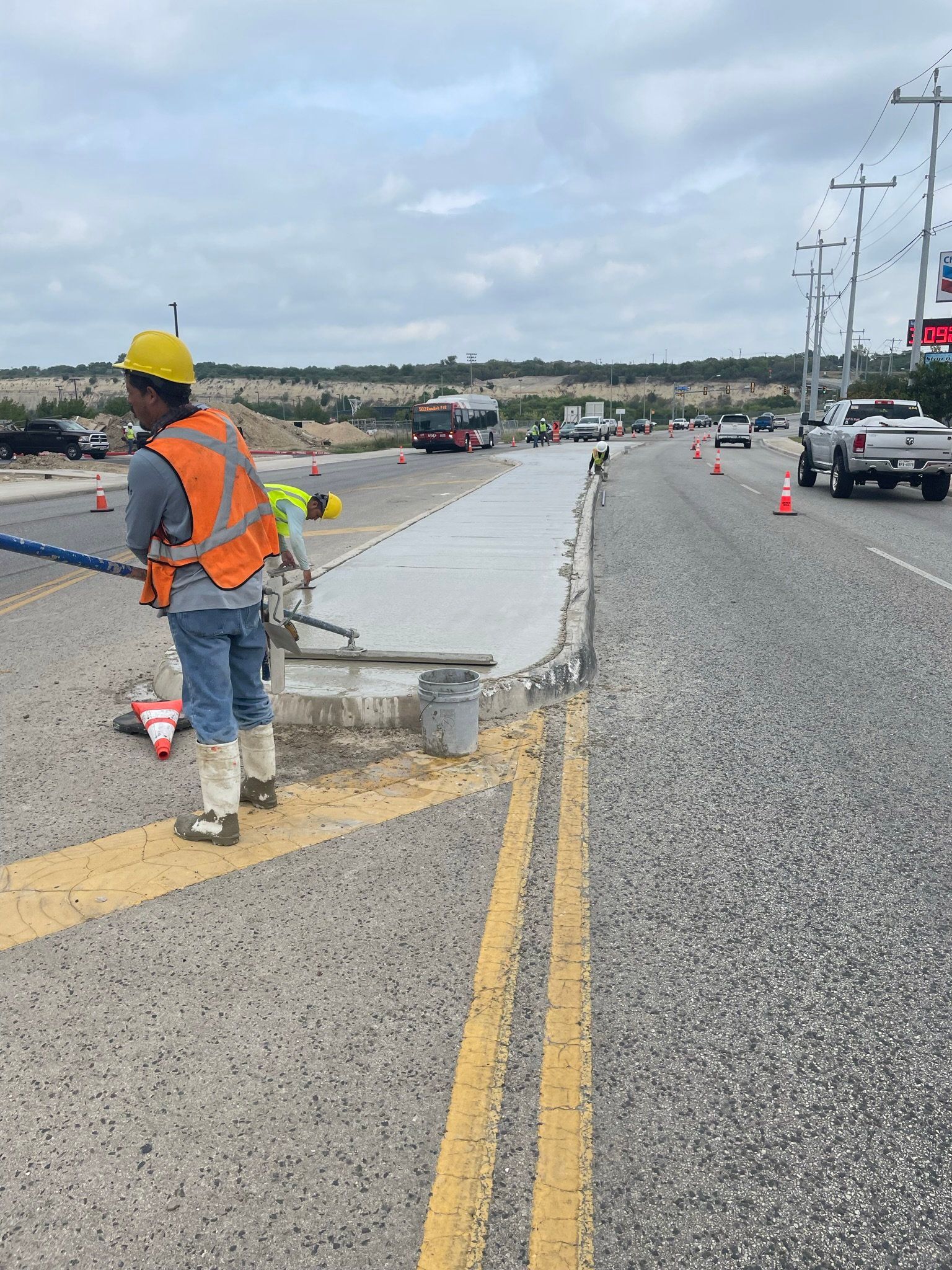 A construction worker is standing on the side of a road.